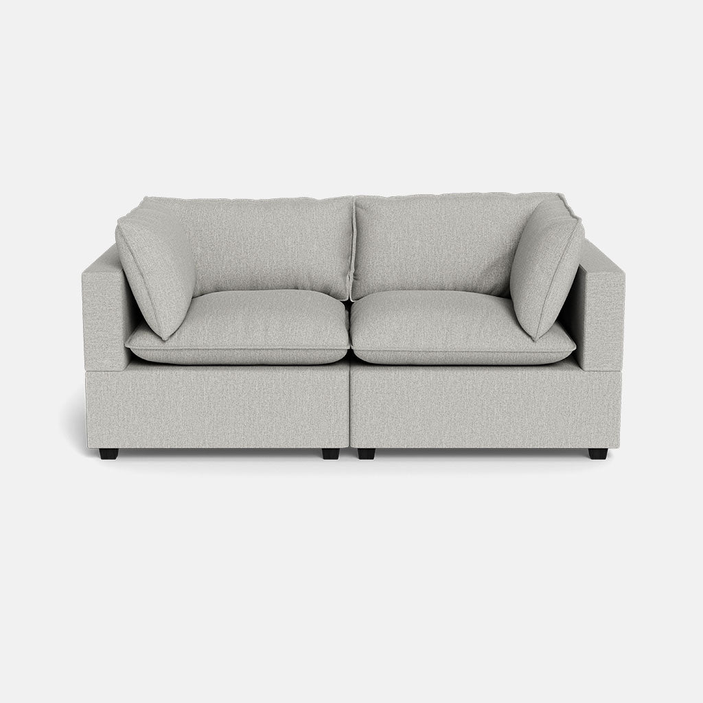 The Kova Pillow Cushion Sofa 86" is a modern, light grey two-seater with square arms and plush cushions, displayed against a plain white background.