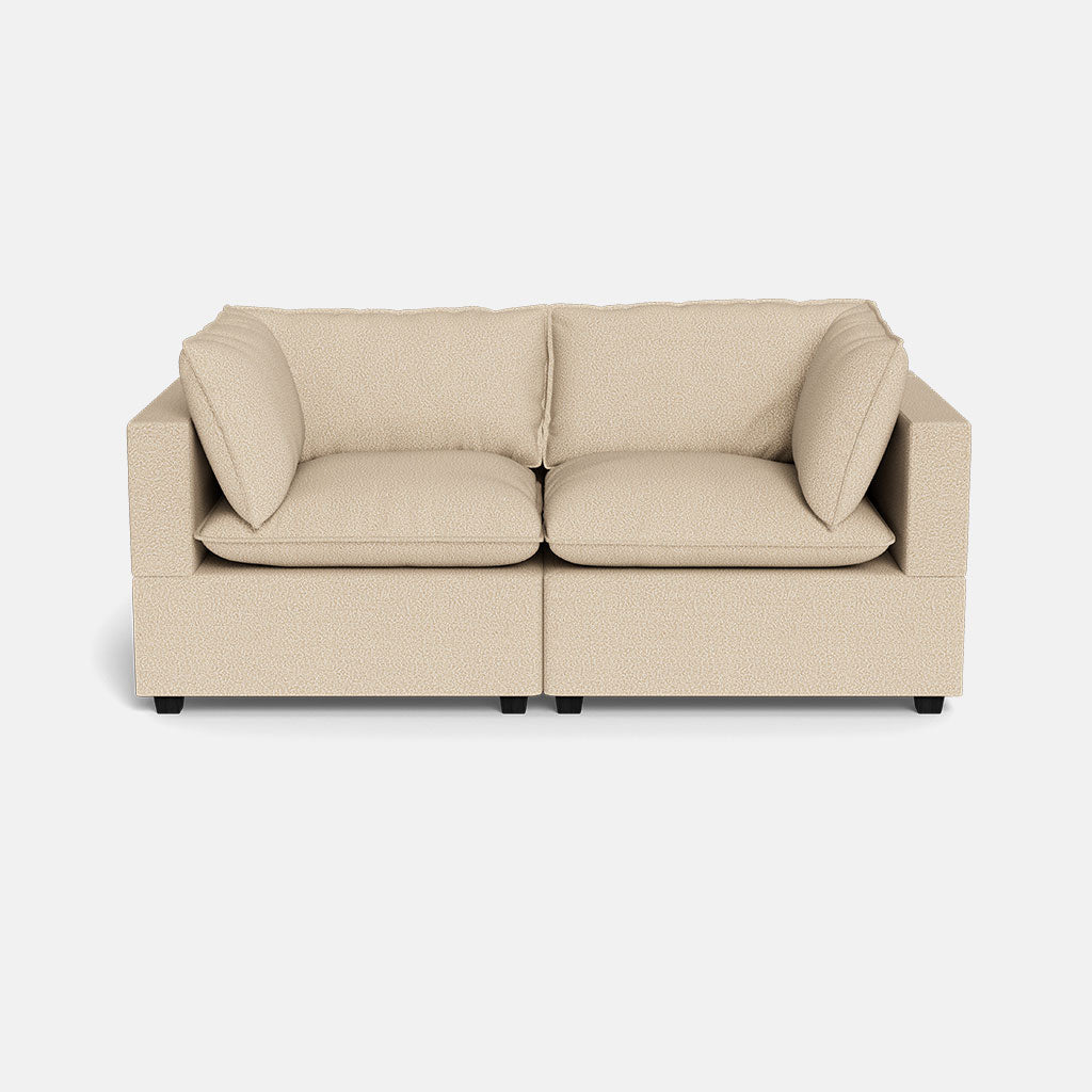 The Kova Pillow Cushion Sofa 86" is a beige two-seater with square arms, two seat cushions, and two back cushions, set against a white background.